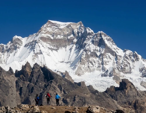Climbers ascending a challenging 7000 meter peak in Nepal, surrounded by snow-covered Himalayan mountains, steep icy slopes, and dramatic high-altitude landscape under a clear blue sky.