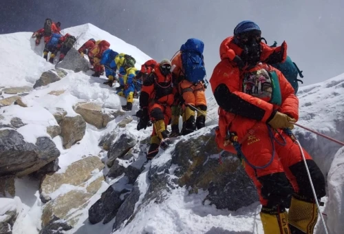 Trekkers climbing toward the summit of Mount Everest on a steep snowy ridge in the Himalayas