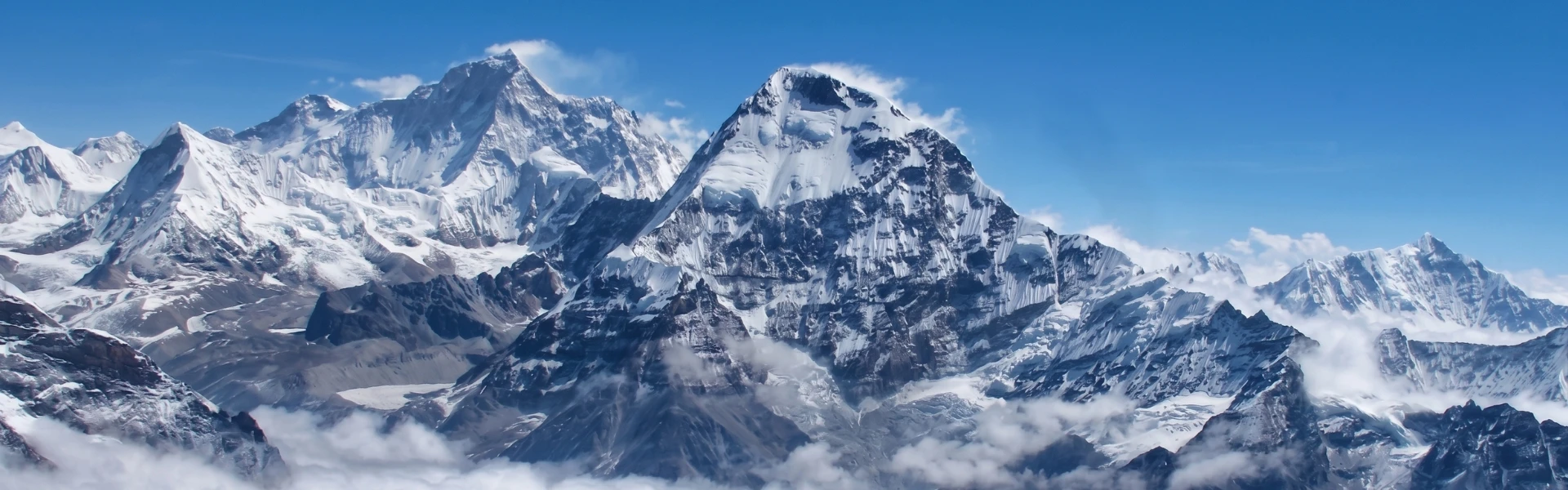 Panoramic view of Mount Makalu and surrounding snow-covered Himalayan peaks under a clear blue sky in eastern Nepal.