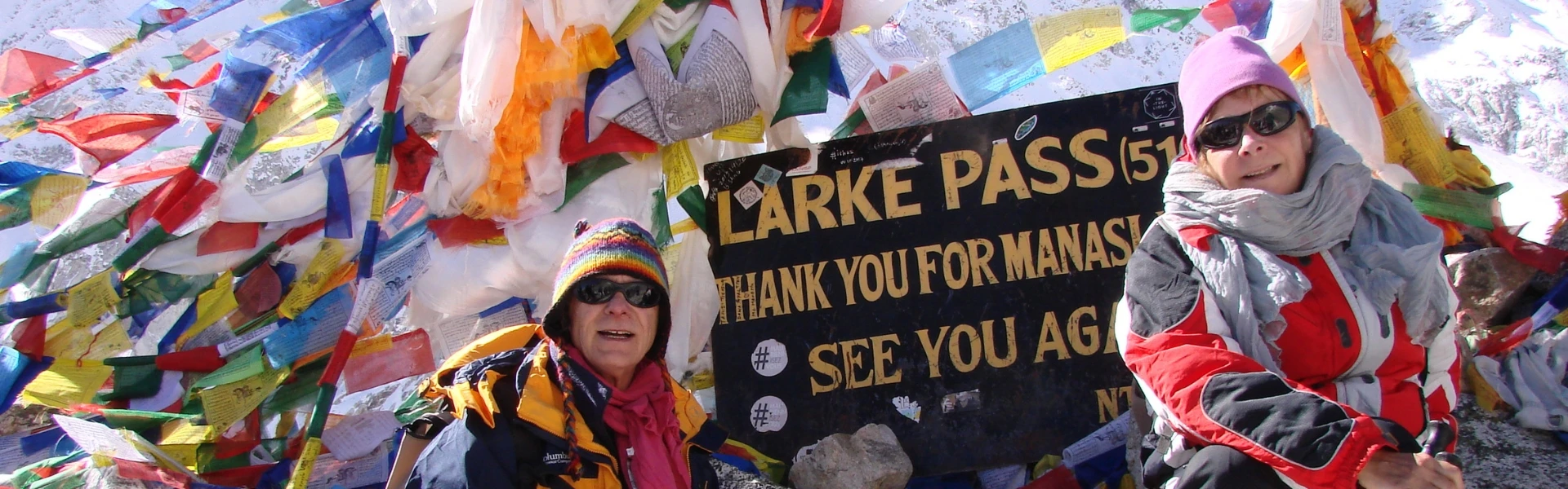 Trekkers crossing Larkya La Pass with snow-covered peaks and dramatic Himalayan landscape in the Manaslu region