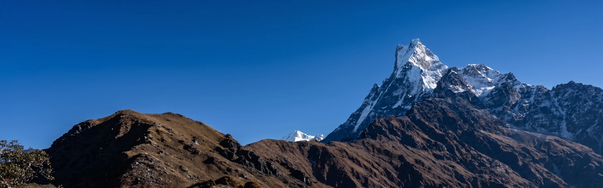 Mardi Himal trek banner showing the stunning snowy peaks of Mardi Himal in the Annapurna region of Nepal with clear blue sky and dramatic Himalayan landscape.