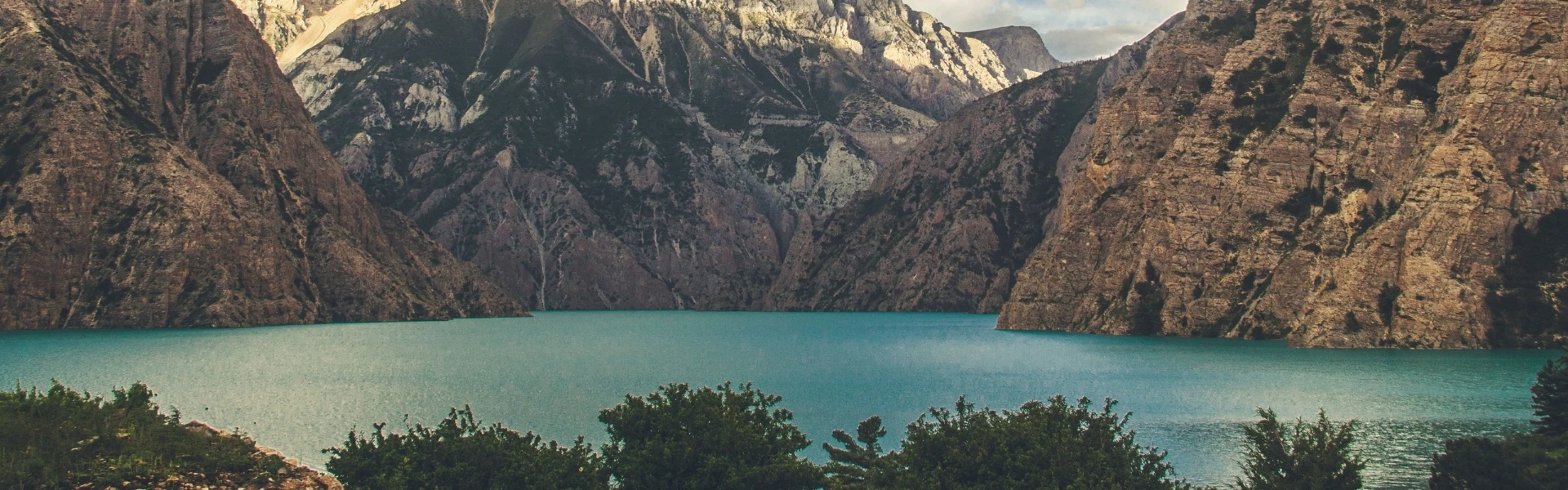 Panoramic view of Shey Phoksundo Lake and the rugged Dolpo mountains under a clear blue sky