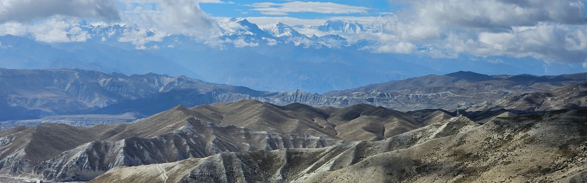 Panoramic view of Upper Mustang's rugged Himalayan desert with colorful cliffs and the ancient Kingdom of Lo Manthang in Nepal.