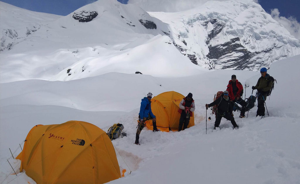 Trekker ascending Chulu East Peak with views of Annapurna massif and Thorong La Pass