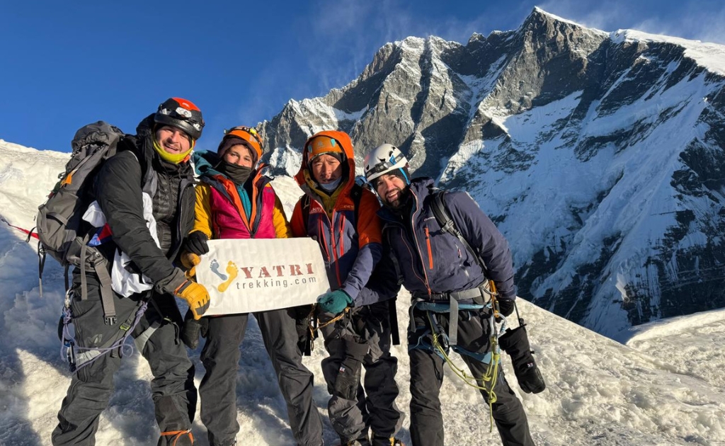 Climbers standing on the summit of Island Peak with panoramic views of Lhotse and surrounding Himalayan peaks