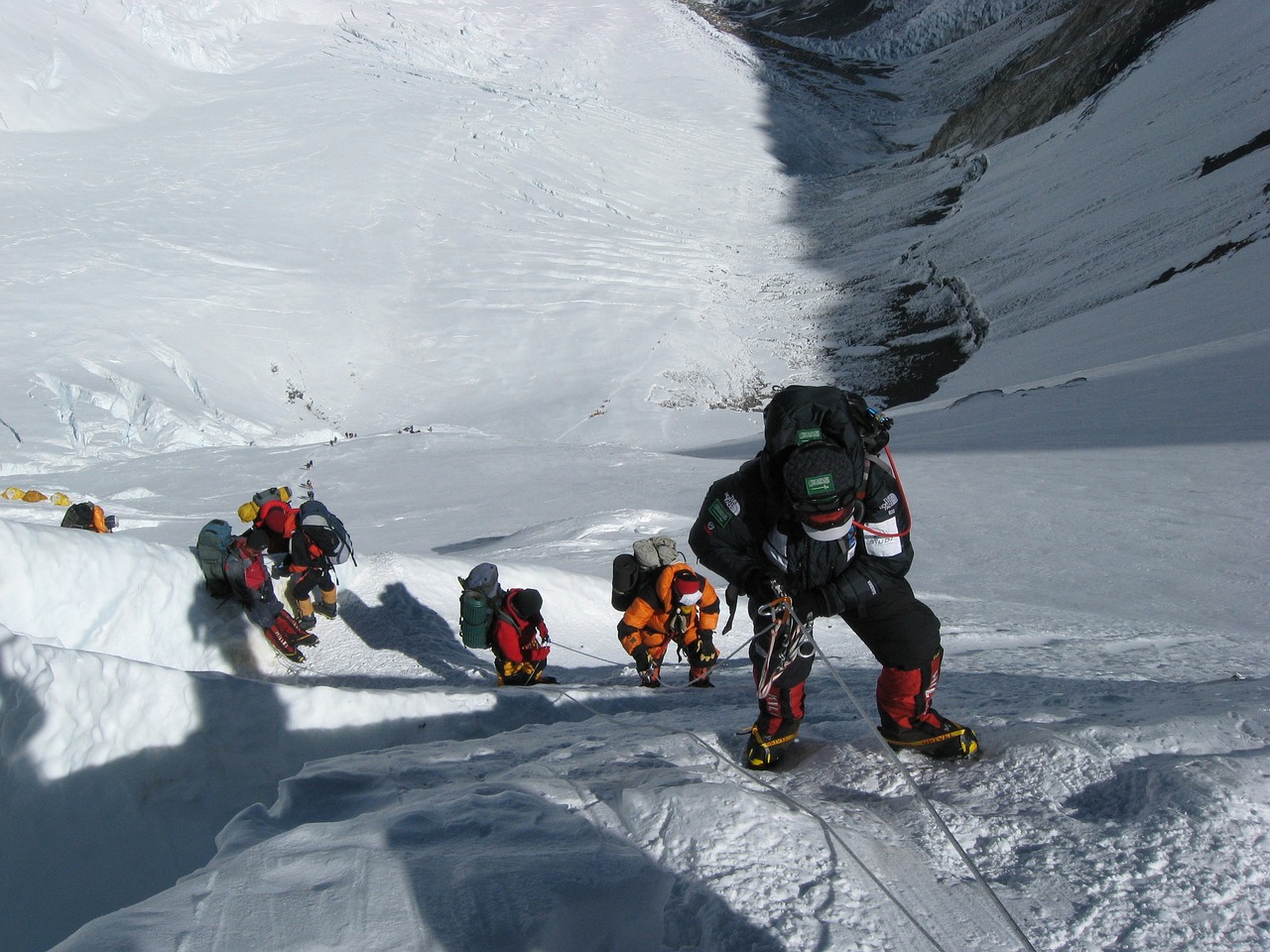 Climber ascending a snowy ridge under Everest’s shadow, symbolizing permit and insurance context.