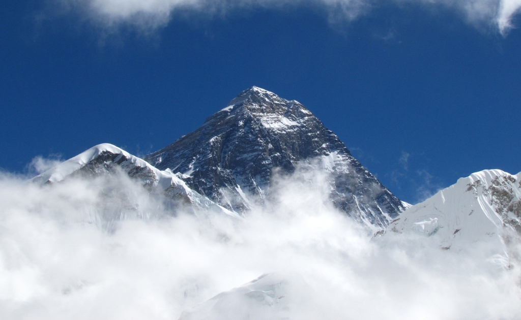 Snow-covered summit of Mount Everest rising above the clouds in the Himalayan range