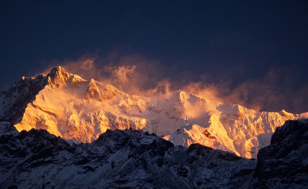 Sunset glow over Mount Kanchenjunga with colorful skies and snowy Himalayan peaks in eastern Nepal.