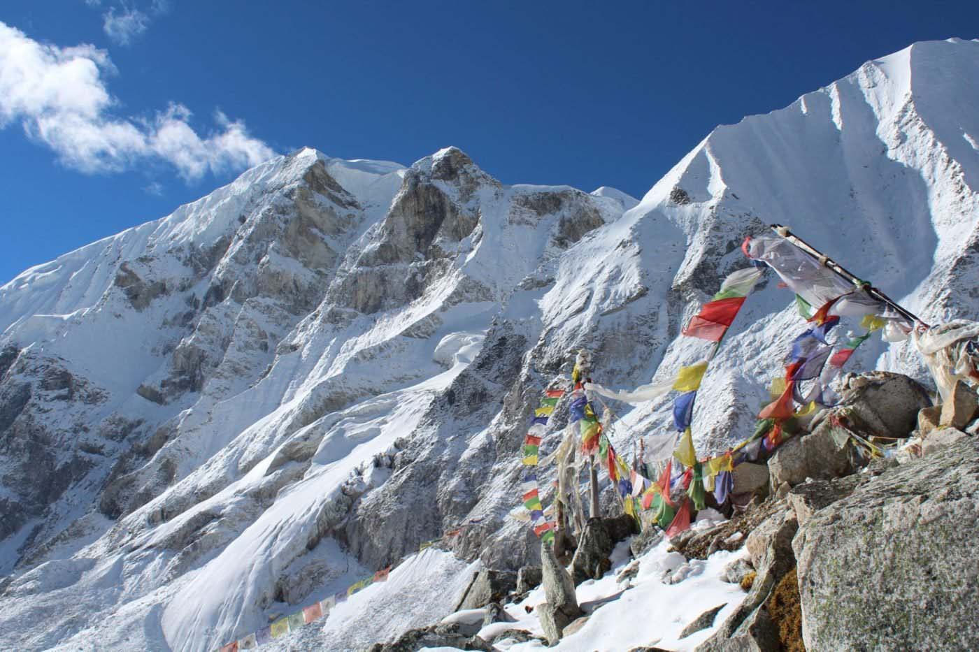 Snow-covered peaks near Larke La Pass with colorful prayer flags overlooking the dramatic Manaslu Range landscape