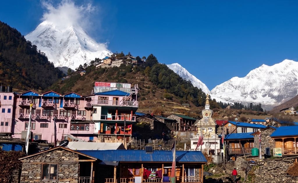Traditional Lho village with stone houses, prayer flags, and Mount Manaslu in the background during the Manaslu Circuit Trek