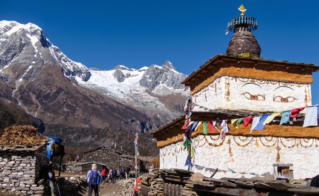 Buddhist chorten with colorful prayer flags along the Manaslu Circuit Trek trail in the Himalayan region of Nepal