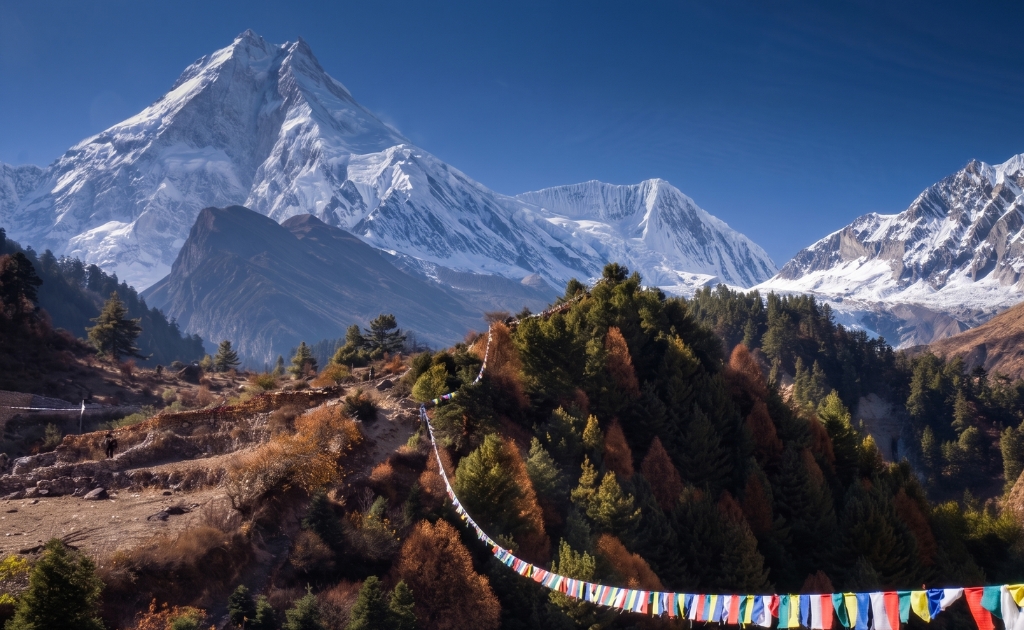 Stunning mountain scenery with prayer flags and traditional villages along the Manaslu trekking route in Nepal
