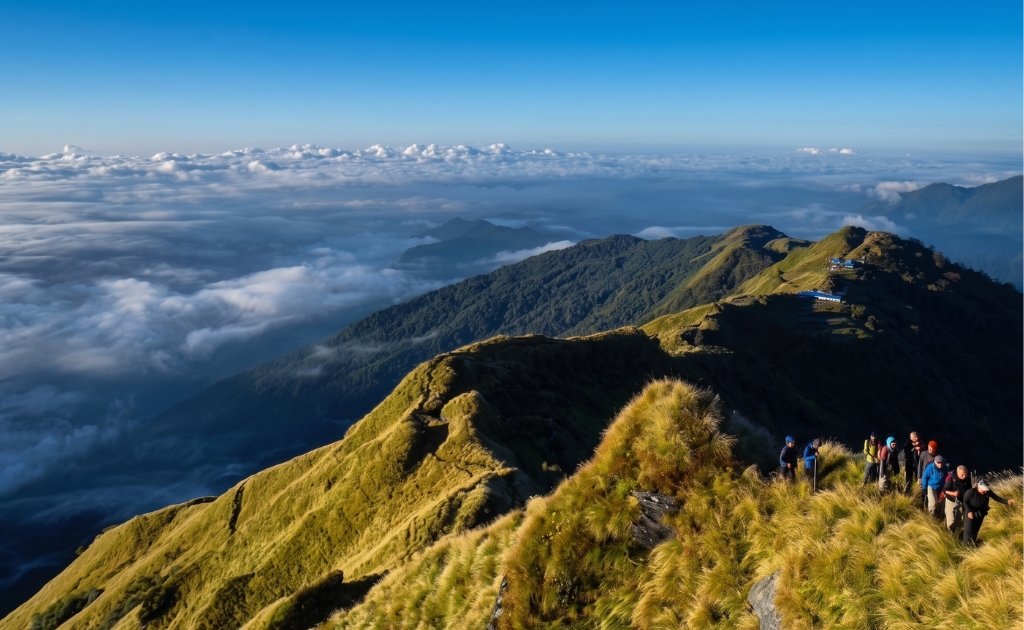 Trekkers hiking along a scenic ridge on the Mardi Himal Trek above a sea of clouds with panoramic mountain views in Nepal