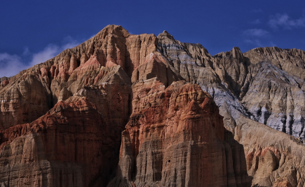 Colorful layered rock formations and dramatic eroded cliffs in Upper Mustang, Nepal, showcasing the region's unique Himalayan desert landscape.
