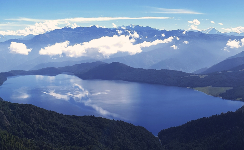 Beautiful panoramic landscape of Rara Lake with calm blue water, green forest, and Himalayan peaks